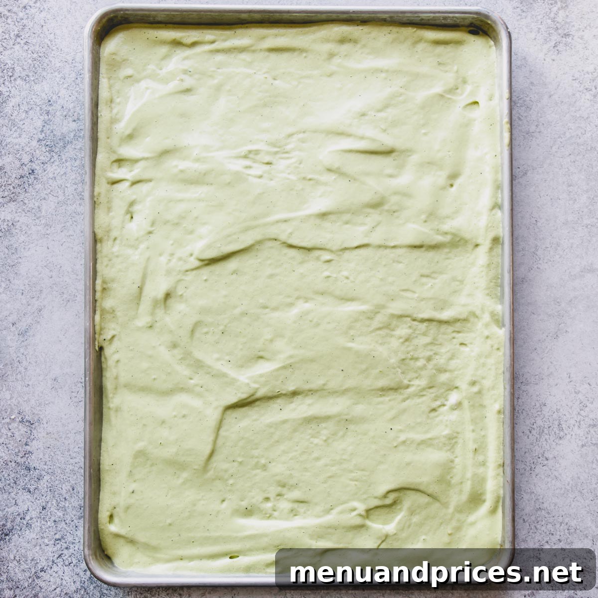Matcha cake batter spread evenly in a baking sheet, ready for baking.