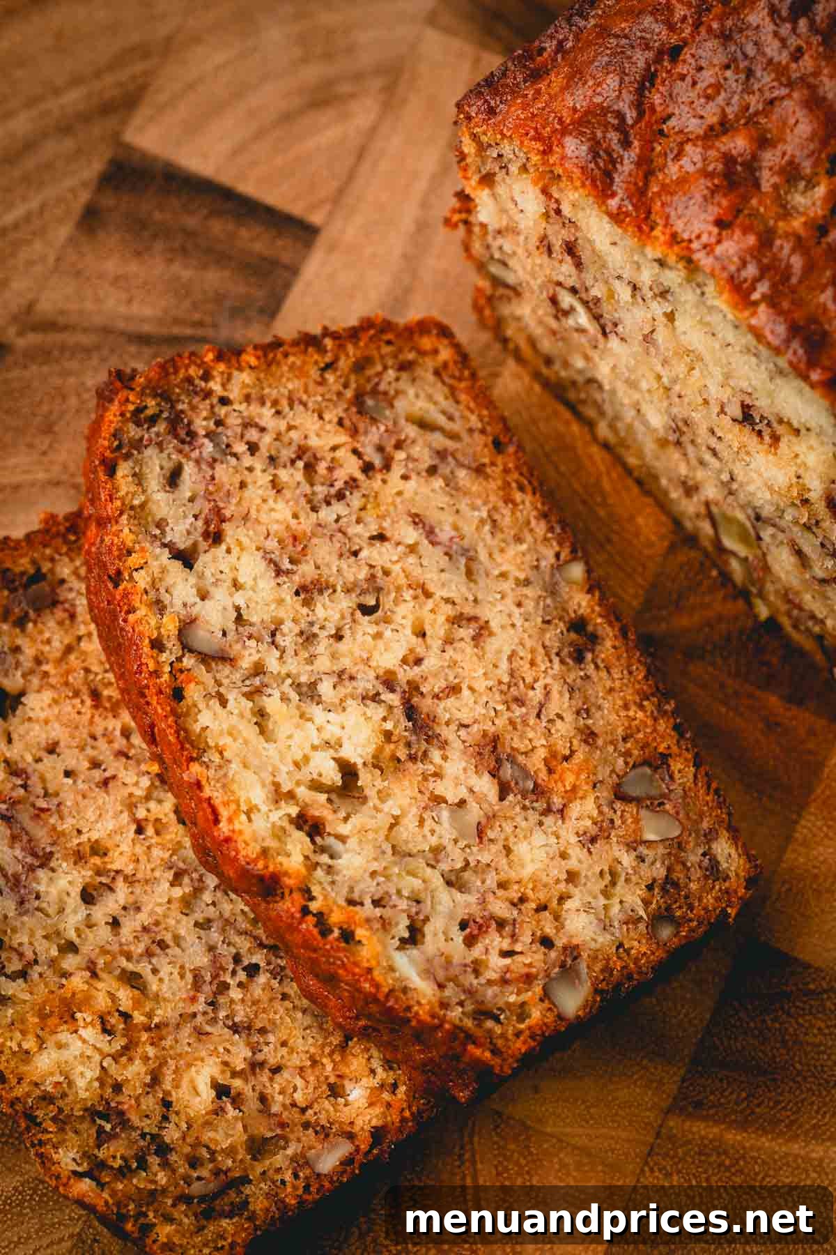 Multiple slices of banana bread, some with pecans, neatly arranged on a wooden cutting board, highlighting its appealing texture and moistness.