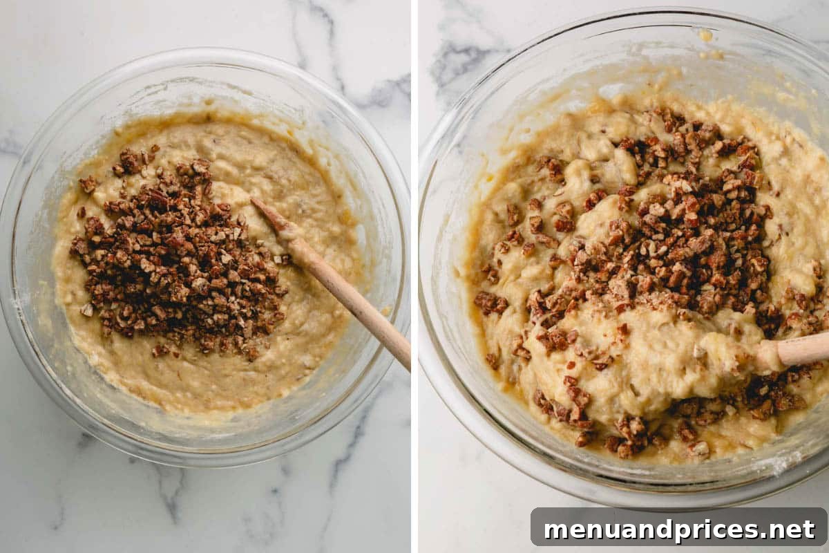 A hand gently folding chopped pecans into a bowl of smooth banana bread batter using a wooden spoon.
