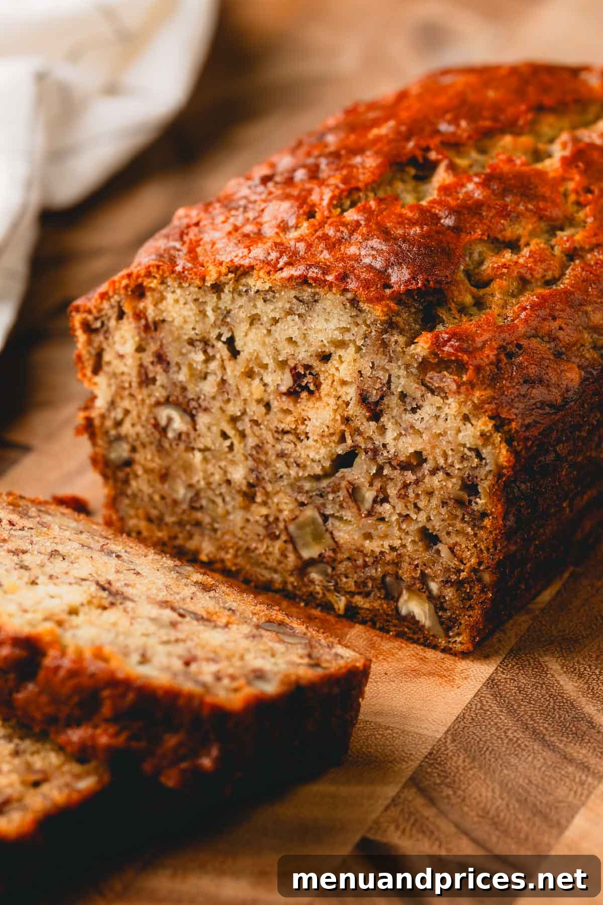 Beautifully cut slices of banana bread resting next to the main loaf on a rustic wooden cutting board, ready to be served.