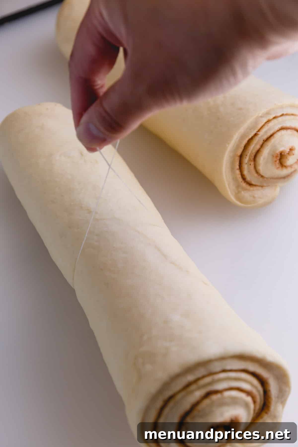 Irresistible Caramel Rolls 13 Two rolls of caramel rolls, one being sliced with dental floss.