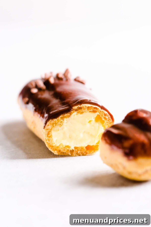 Divine Chocolate Eclairs 4 Sliced chocolate eclair filled with rich pastry cream, showing its airy interior.