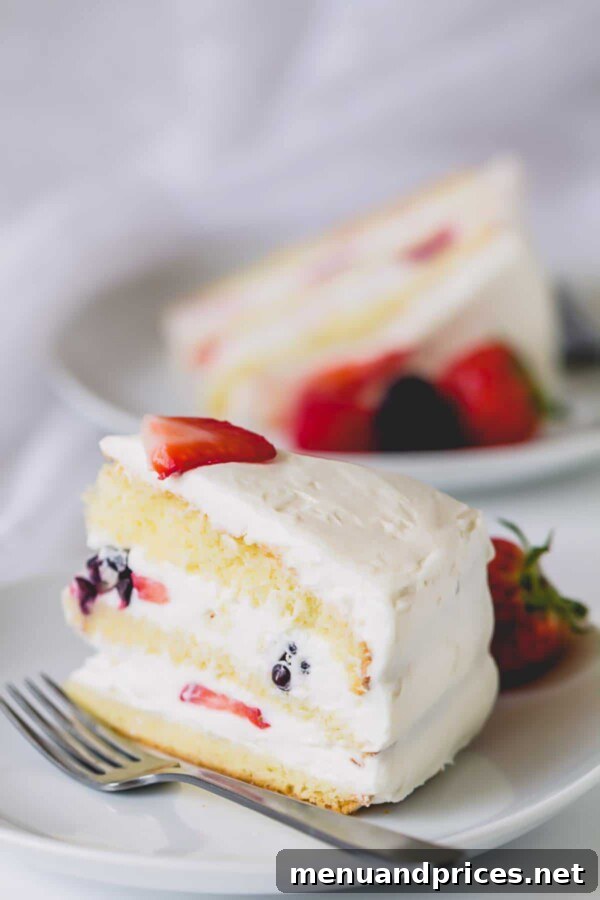 Fresh Berry Chantilly Delight 9 A slice of a beautiful 3-layer Berry Chantilly Cake on a plate, showcasing its colorful filling.