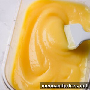 Creamy lemon curd in a clear storage container, ready to be enjoyed.