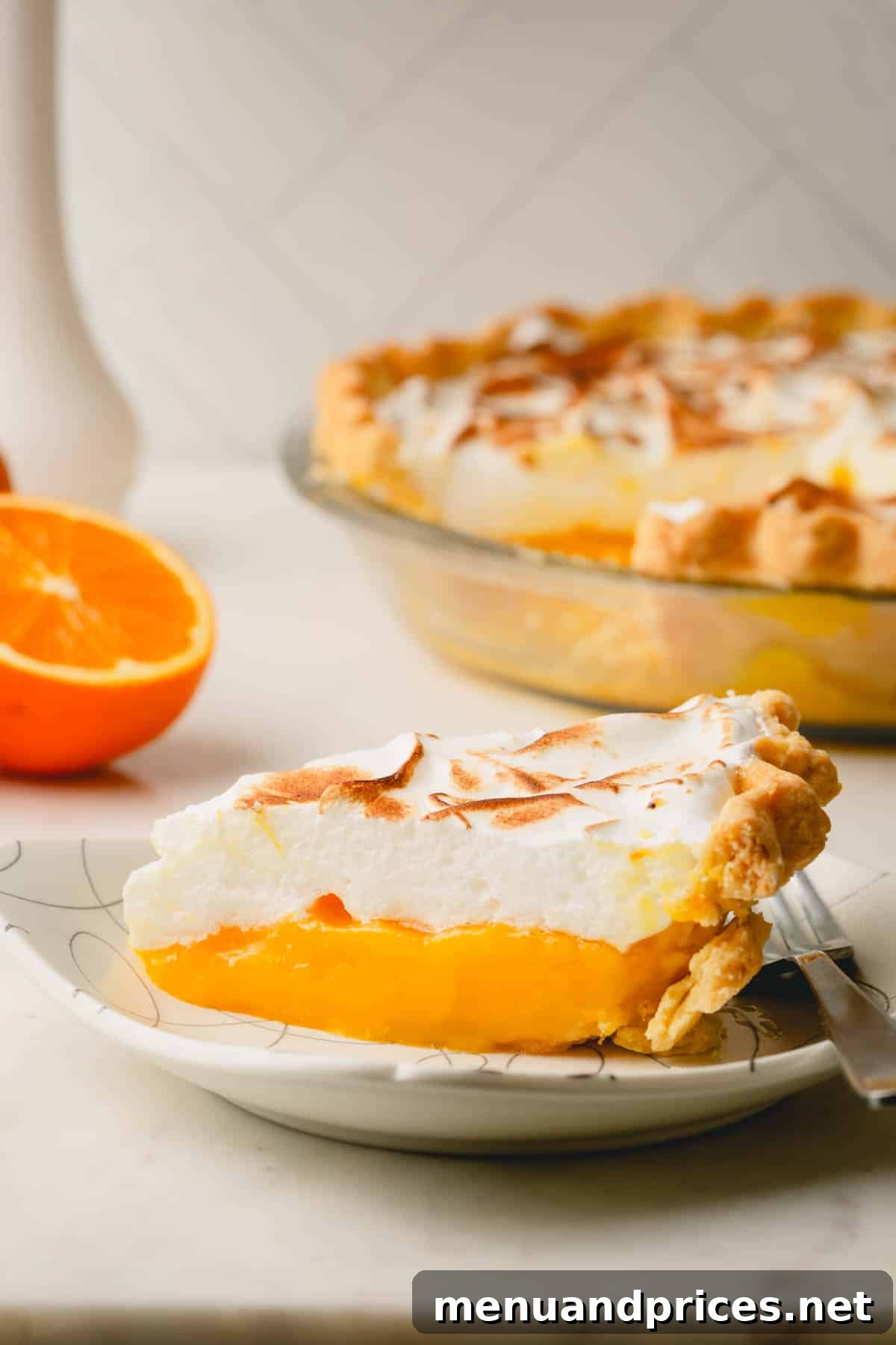 Zesty Orange Cloud Pie 13 A beautiful slice of orange meringue pie presented on a plate, with the rest of the pie subtly blurred in the background.