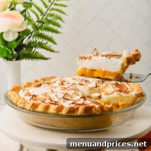 A slice of orange meringue pie being lifted from a pan full of the rest of the pie.
