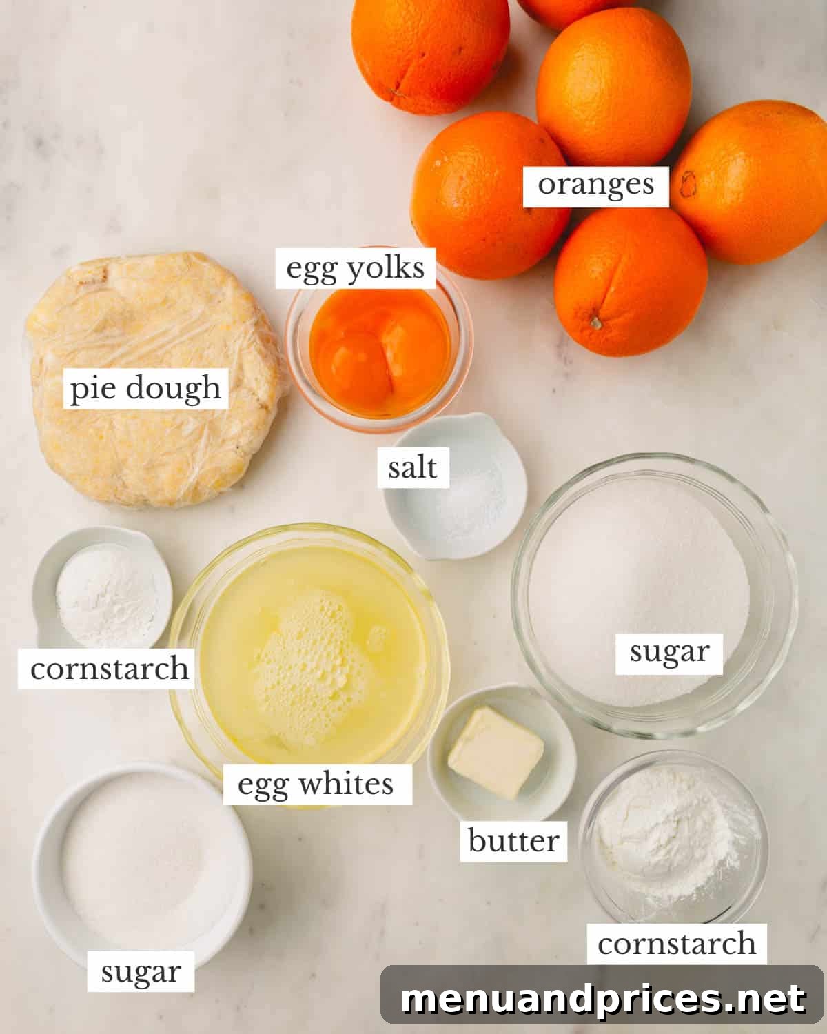 Zesty Orange Cloud Pie 4 A collection of fresh ingredients laid out, ready to make an orange meringue pie, including oranges, eggs, and butter.