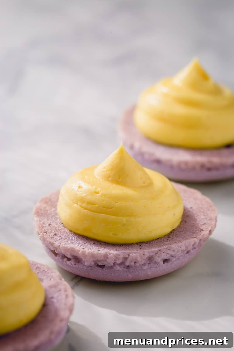Effortless French Buttercream 3 Delicate macaron halves adorned with generous dollops of pale yellow French buttercream.