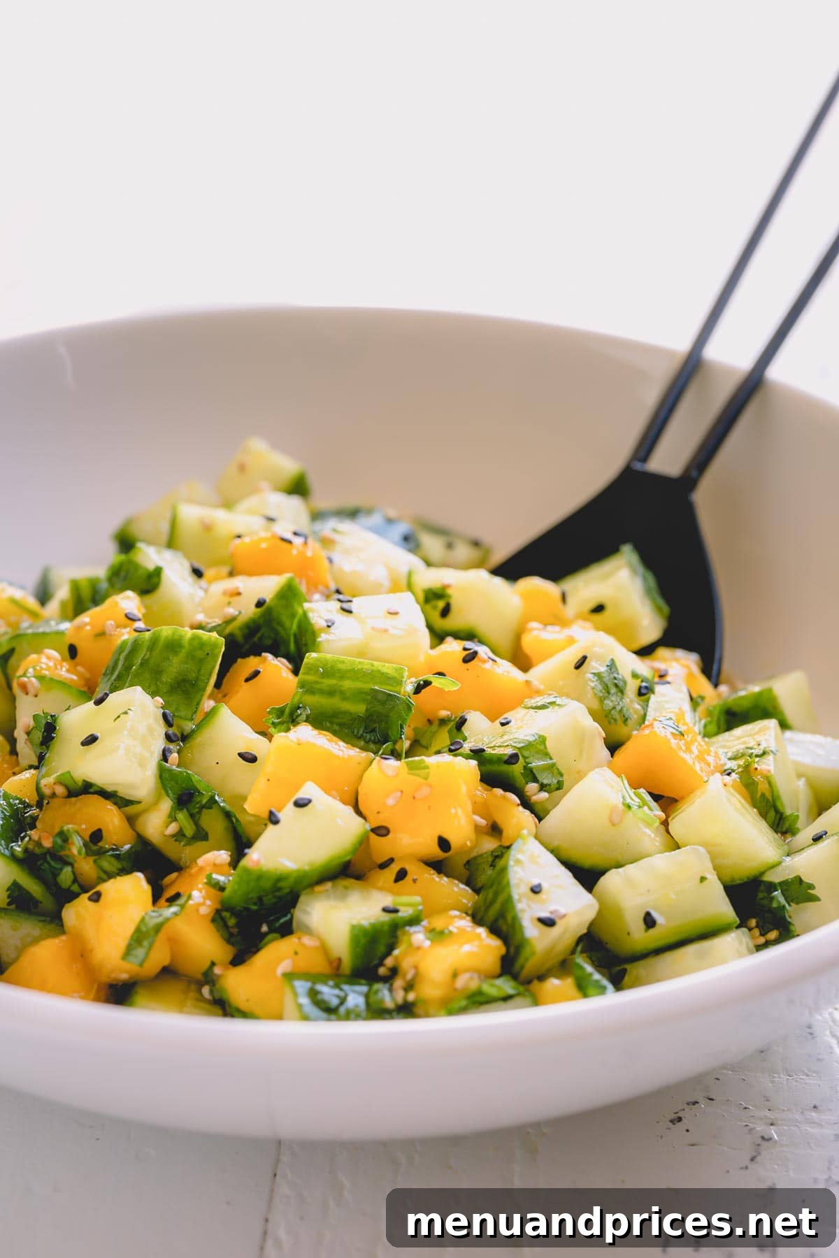 Tropical Mango Cucumber Medley 2 A beautifully presented cucumber mango salad in a pristine white salad bowl, ready to be served.