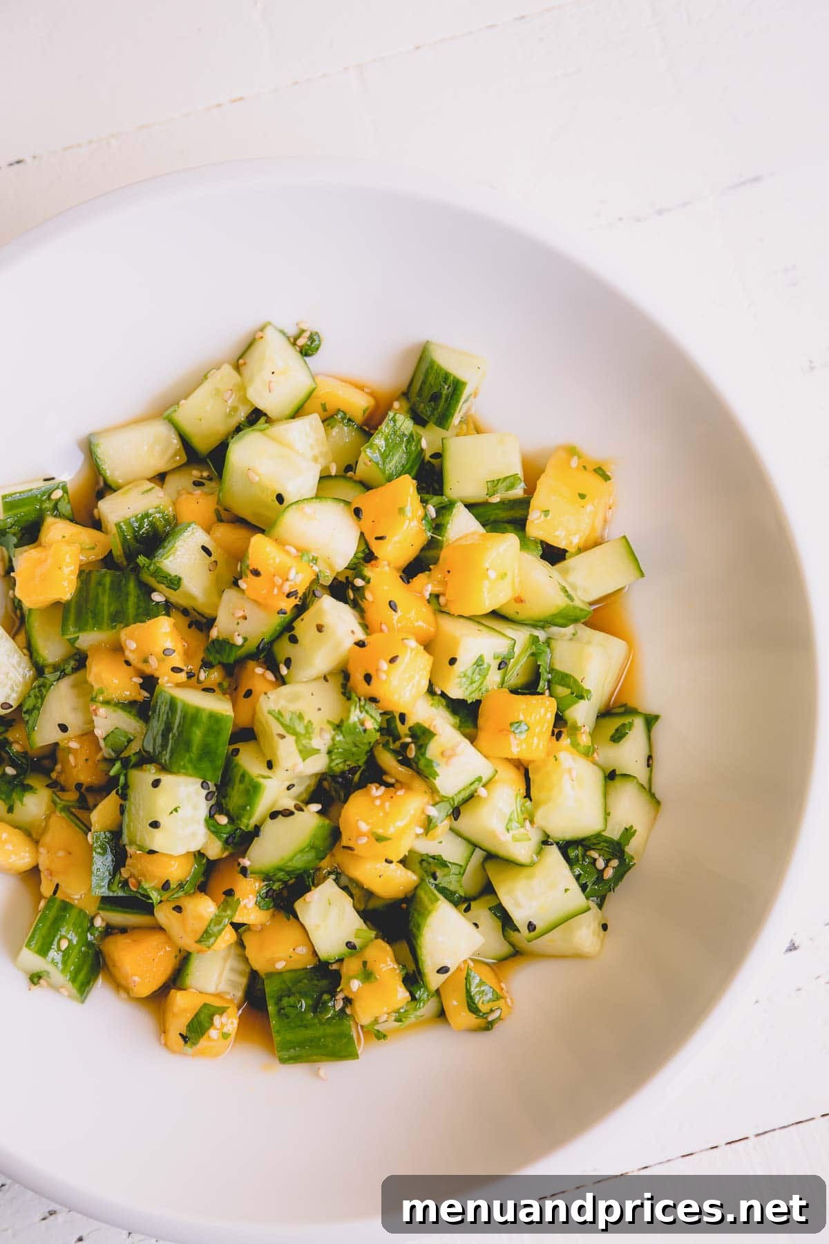 Tropical Mango Cucumber Medley 5 Individual serving of cucumber mango salad on a white plate, garnished with fresh cilantro.