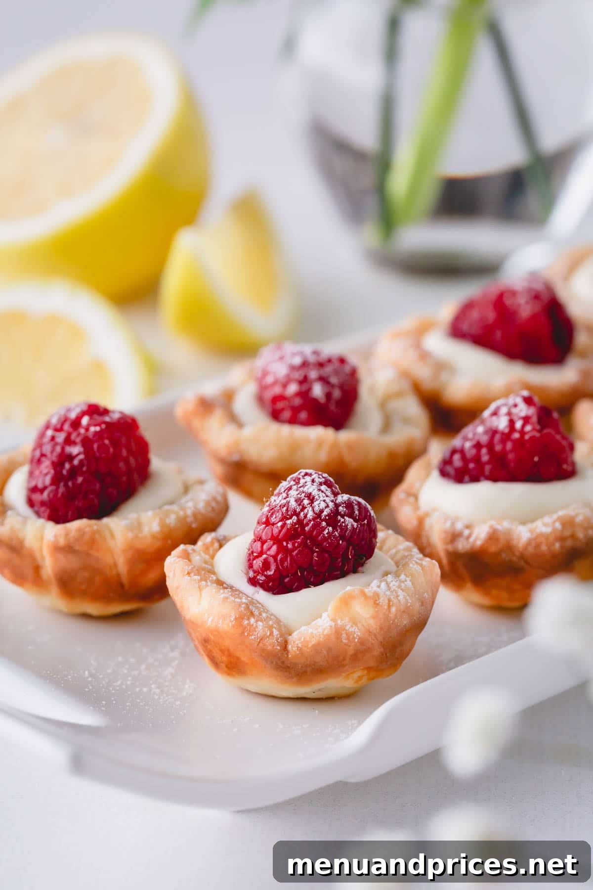 Sun-Kissed Raspberry Lemon Bites 2 Exquisitely arranged raspberry lemon tartlets on a rectangular serving platter, showcasing their vibrant colors and perfect individual portions.