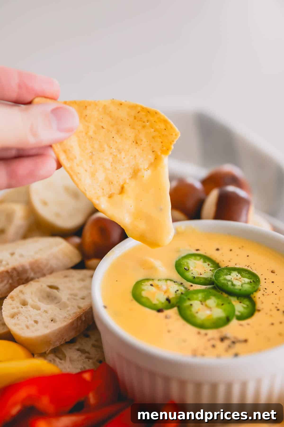 Cheddar Jalapeno Dip 3 A hand dipping a chip into spicy cheddar dip.