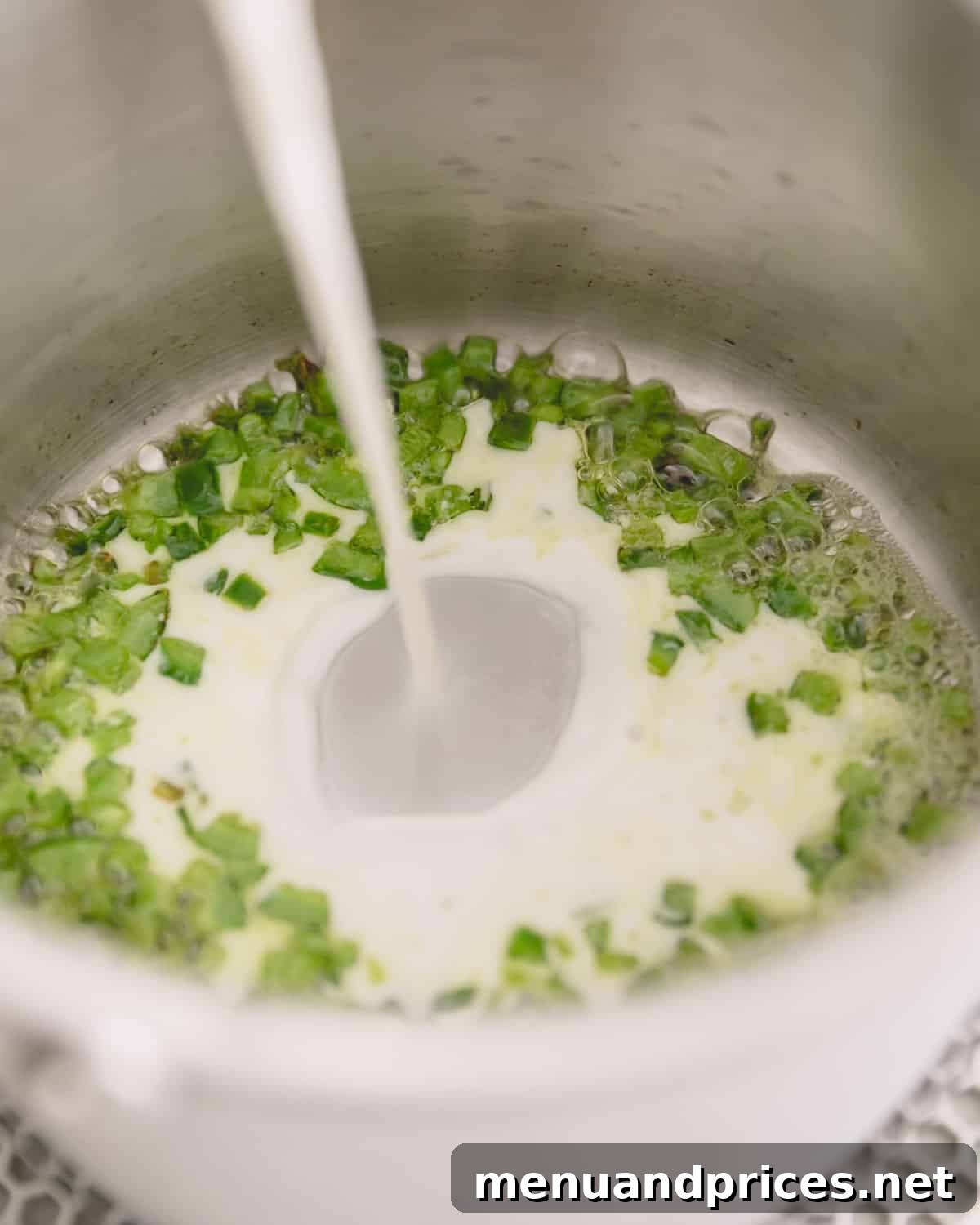 Cheddar Jalapeno Dip 7 Milk going into the saucepan with cooking jalalpeno.