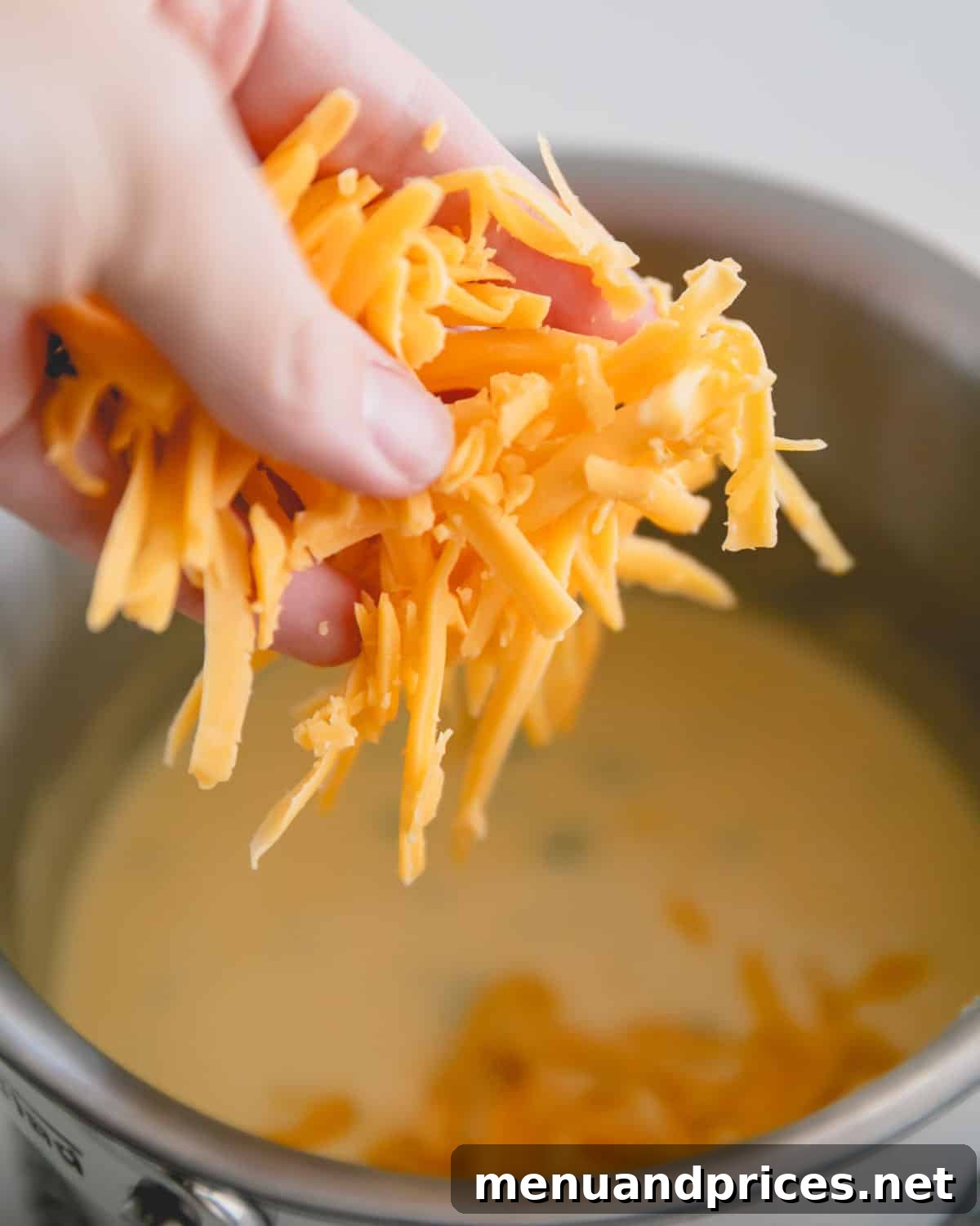 Cheddar Jalapeno Dip 9 A hand adding shredded cheddar cheese.