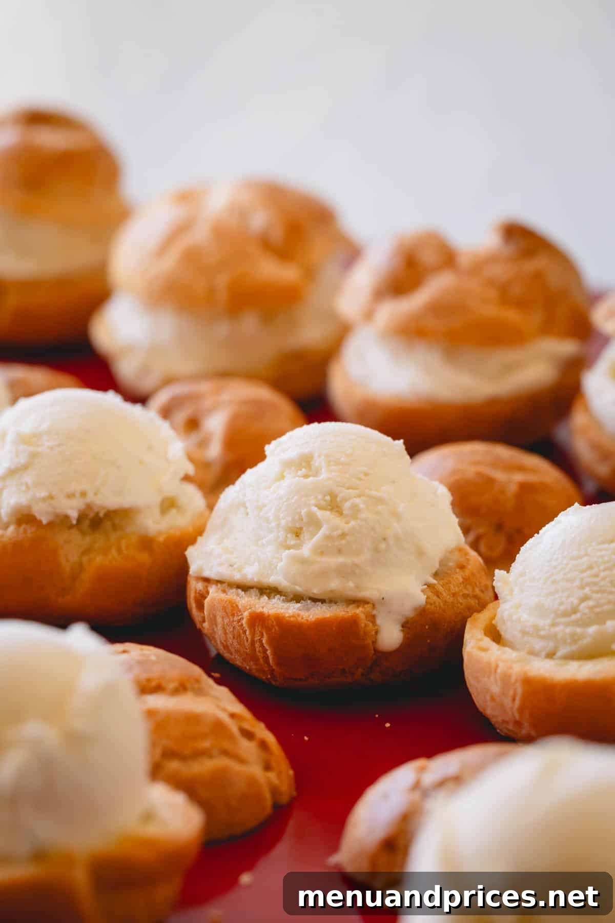 Profiteroles being filled with scoops of creamy vanilla ice cream.