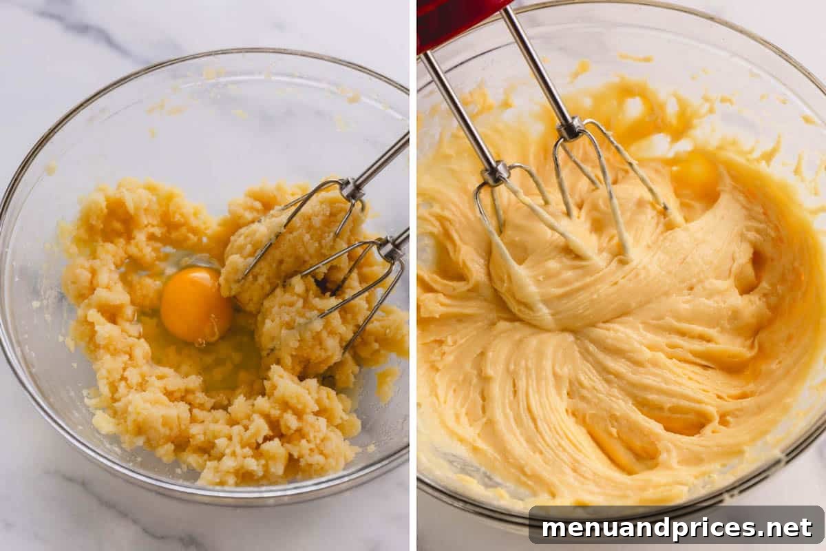An egg being carefully added to the choux pastry dough in a mixer bowl.