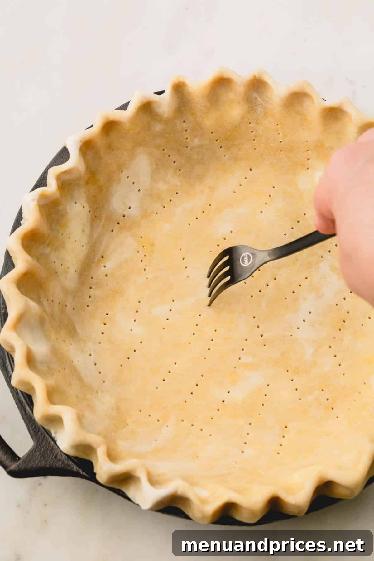 Pure Butter Flaky Pie Pastry 9 Raw pie crust in a pie dish with neatly crimped edges, meticulously pierced with a fork to prevent bubbling during baking.