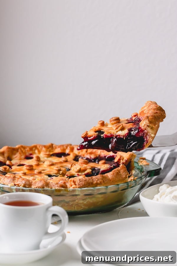 A close-up of a slice of homemade sweet cherry pie, revealing the rich, thick cherry filling and layers of tender, flaky pastry.