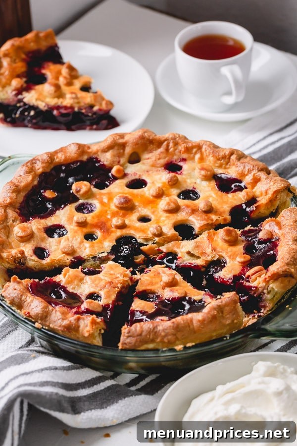 A finished, baked sweet cherry pie, freshly out of the oven, with a glistening, golden crust and a hint of the delicious cherry filling visible.