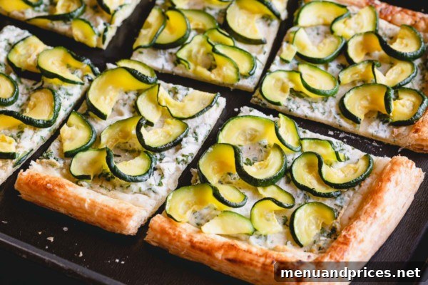 Summer Zucchini Ricotta Tart 7 A freshly baked zucchini ricotta tart on a baking sheet, with a few slices cut and ready to serve.