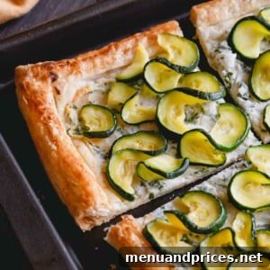 A close-up shot of the golden-brown zucchini ricotta tart on a baking sheet.