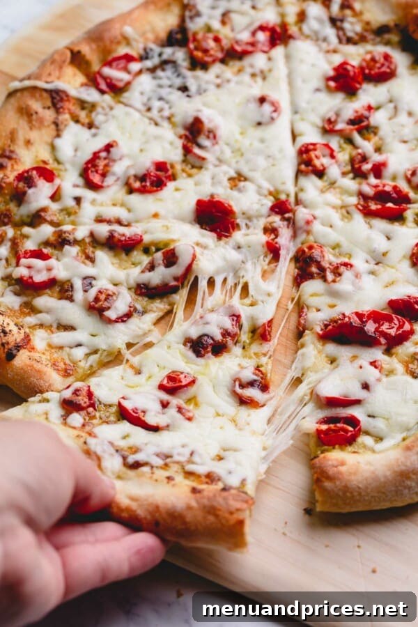Slow-Roasted Tomato & Golden Mozzarella Pizza 2 Sliced pesto cherry tomato pizza with a delightful cheese pull, showcasing its gooey melted mozzarella and perfectly golden crust.