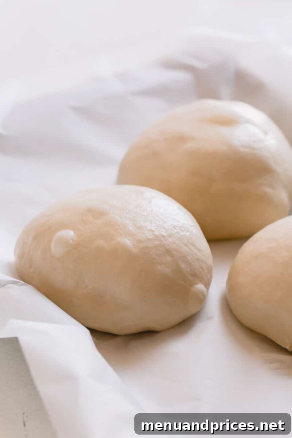 Slow-Roasted Tomato & Golden Mozzarella Pizza 6 Close-up of hands stretching pizza dough on a floured surface, demonstrating the preparation step for a perfect crust.