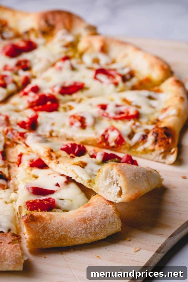 Slow-Roasted Tomato & Golden Mozzarella Pizza 8 A perfectly sliced pesto cherry tomato pizza with a visible airy, crispy crust, showcasing its delicious texture.