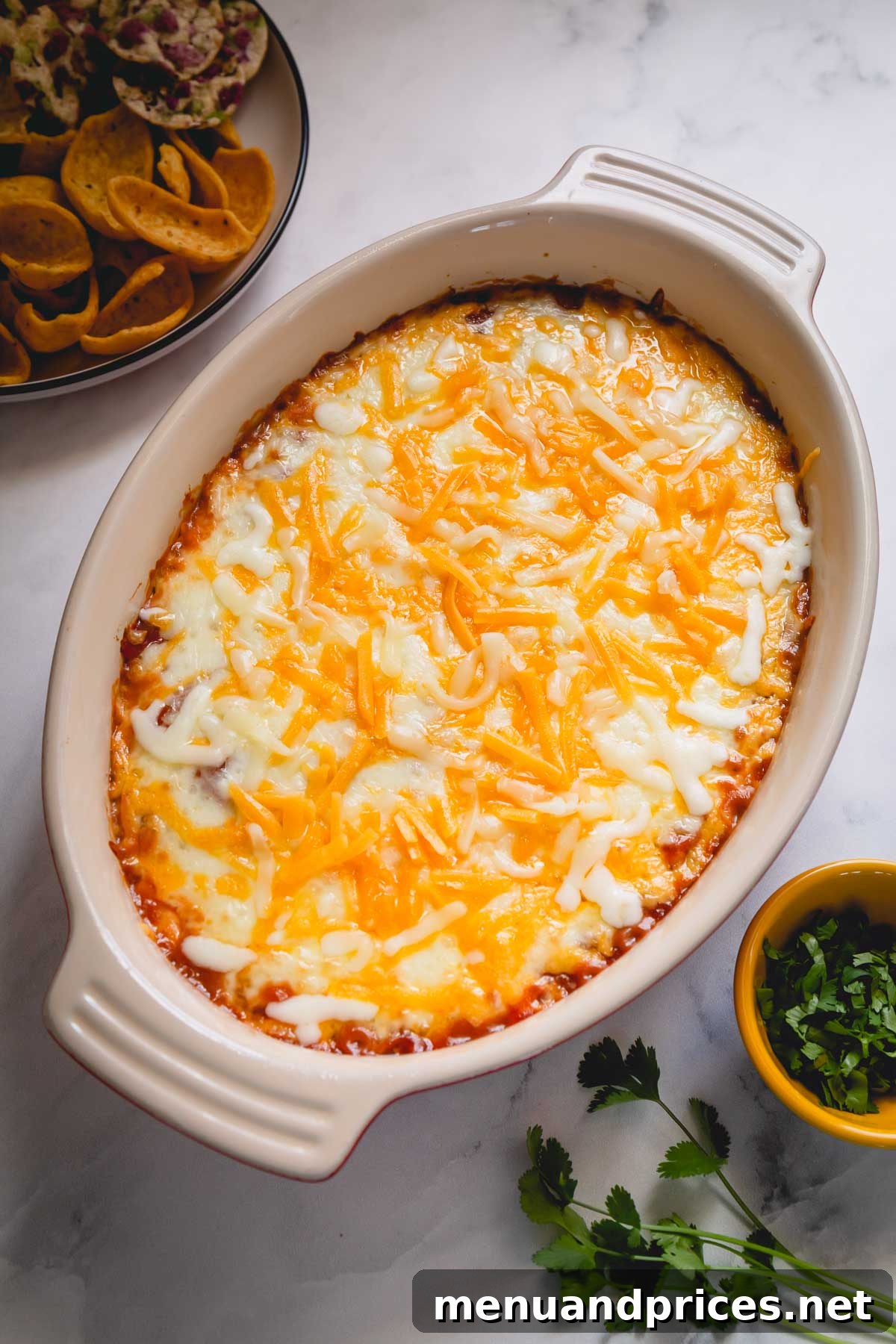 Effortless Cheesy Bean Dip 4 A large, inviting casserole dish filled with golden-brown, bubbly bean dip, ready to be served. The cheese topping is perfectly melted and slightly browned.