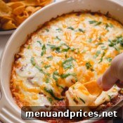 Bean dip in a casserole dish with a portion being scooped with a chip.