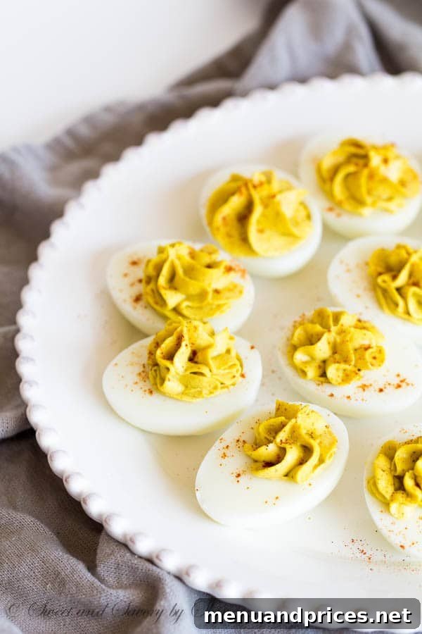 Beautifully piped curry deviled eggs garnished with smoked paprika, ready to be served on a platter.