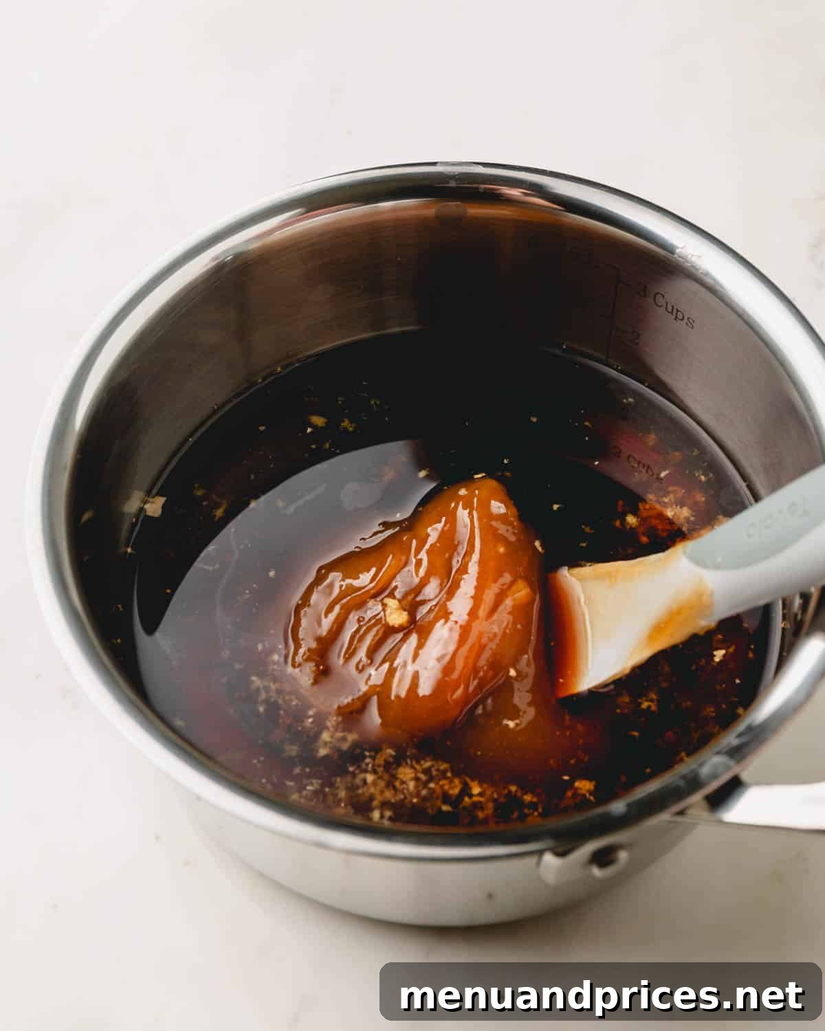 Sticky Teriyaki Chicken Wings 9 A wooden spoon stirs raw honey into a simmering pot of teriyaki sauce on a stovetop, capturing the glistening texture of the developing sauce.