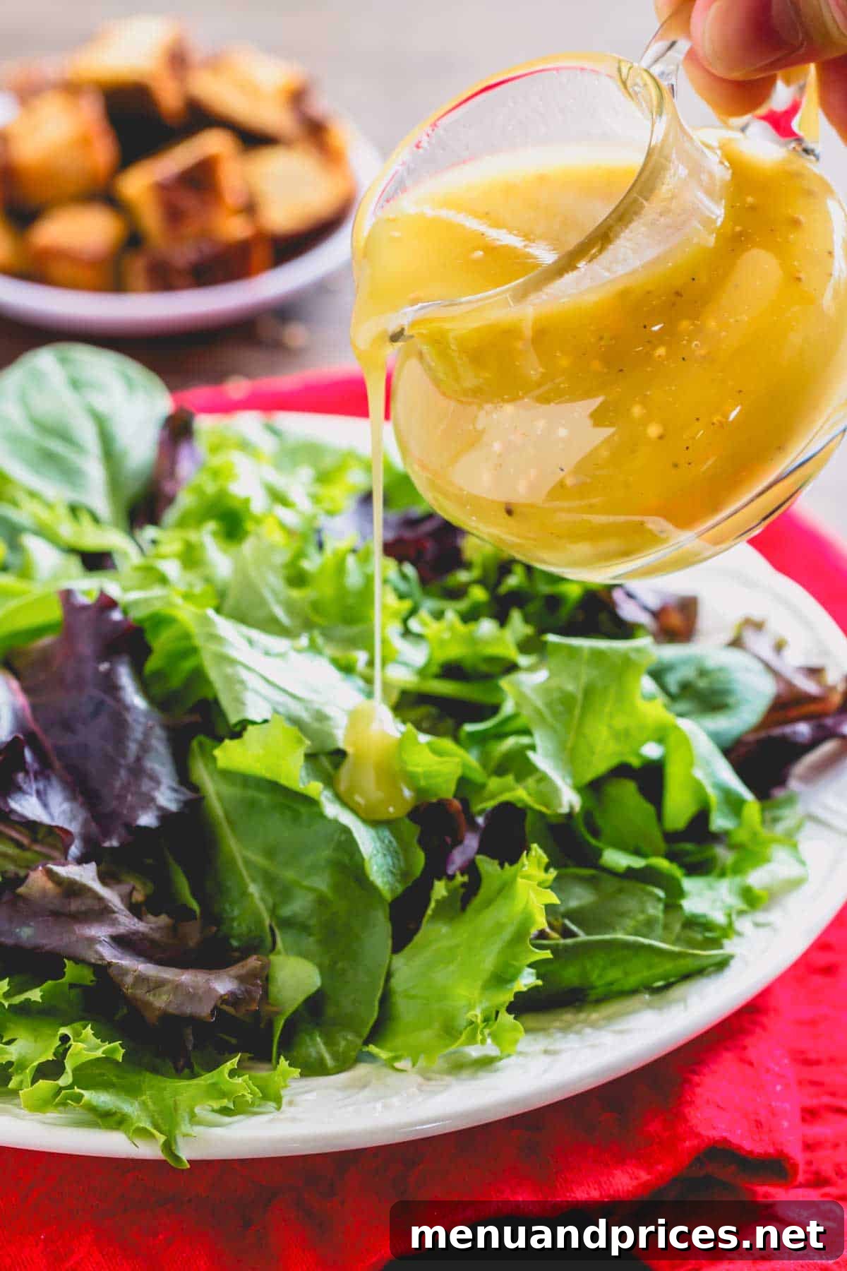 Sweet & Tangy Homemade Honey Dijon Dressing 3 Creamy honey Dijon dressing being drizzled generously over a fresh green salad.