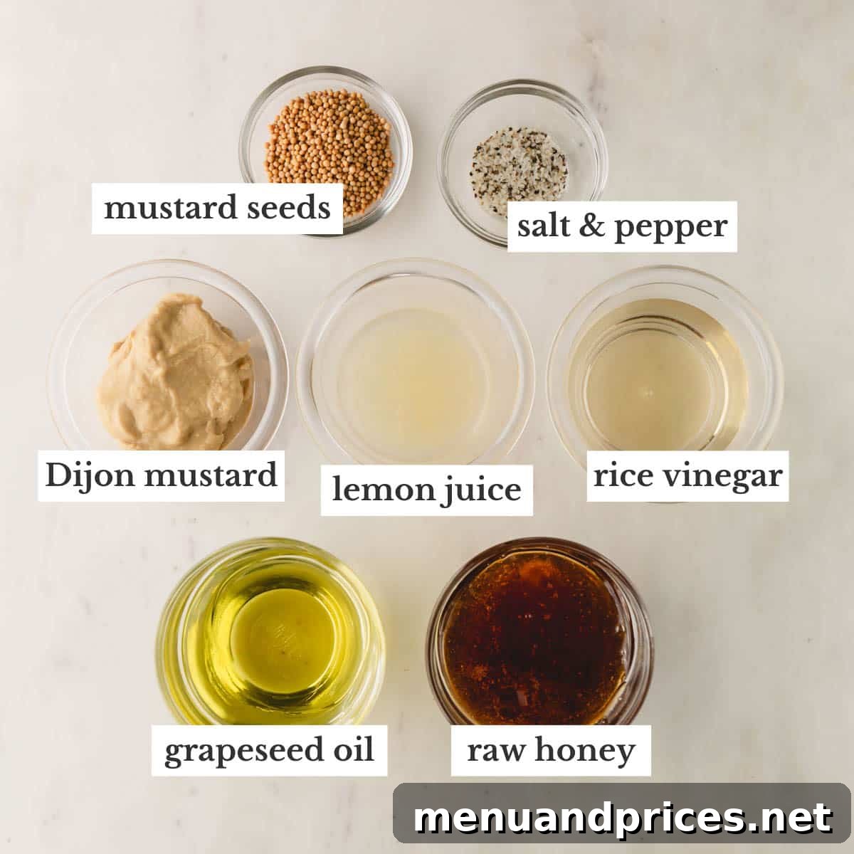 Sweet & Tangy Homemade Honey Dijon Dressing 4 A collection of fresh ingredients laid out, including a bottle of oil, honey, rice vinegar, Dijon mustard, lemon, and mustard seeds, for making homemade Honey Dijon dressing.