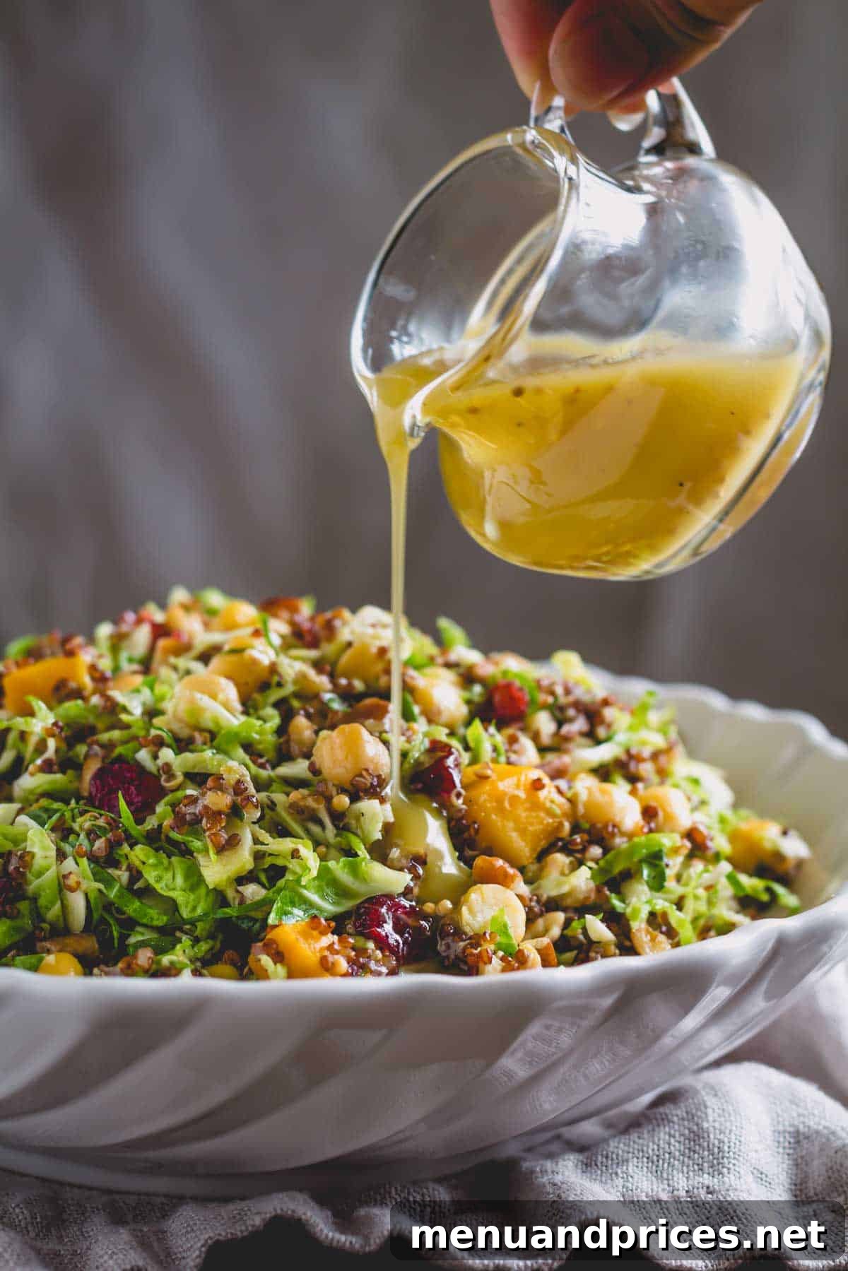 Roasted Brussels Quinoa Harvest Bowl 3 Honey Dijon dressing being drizzled over a warm quinoa Brussels sprouts salad in a serving bowl.