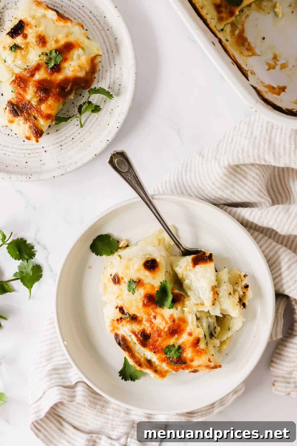 Creamy Cheesy Potato Gratin 6 A plate of cheesy scalloped potatoes with a fork taking a bite.