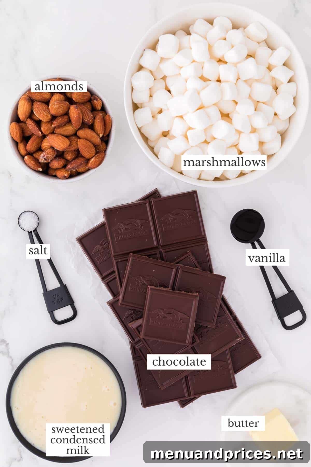 Creamy Rocky Road Indulgence 3 A collection of fresh ingredients laid out for making rocky road fudge, including chocolate, marshmallows, almonds, and butter.