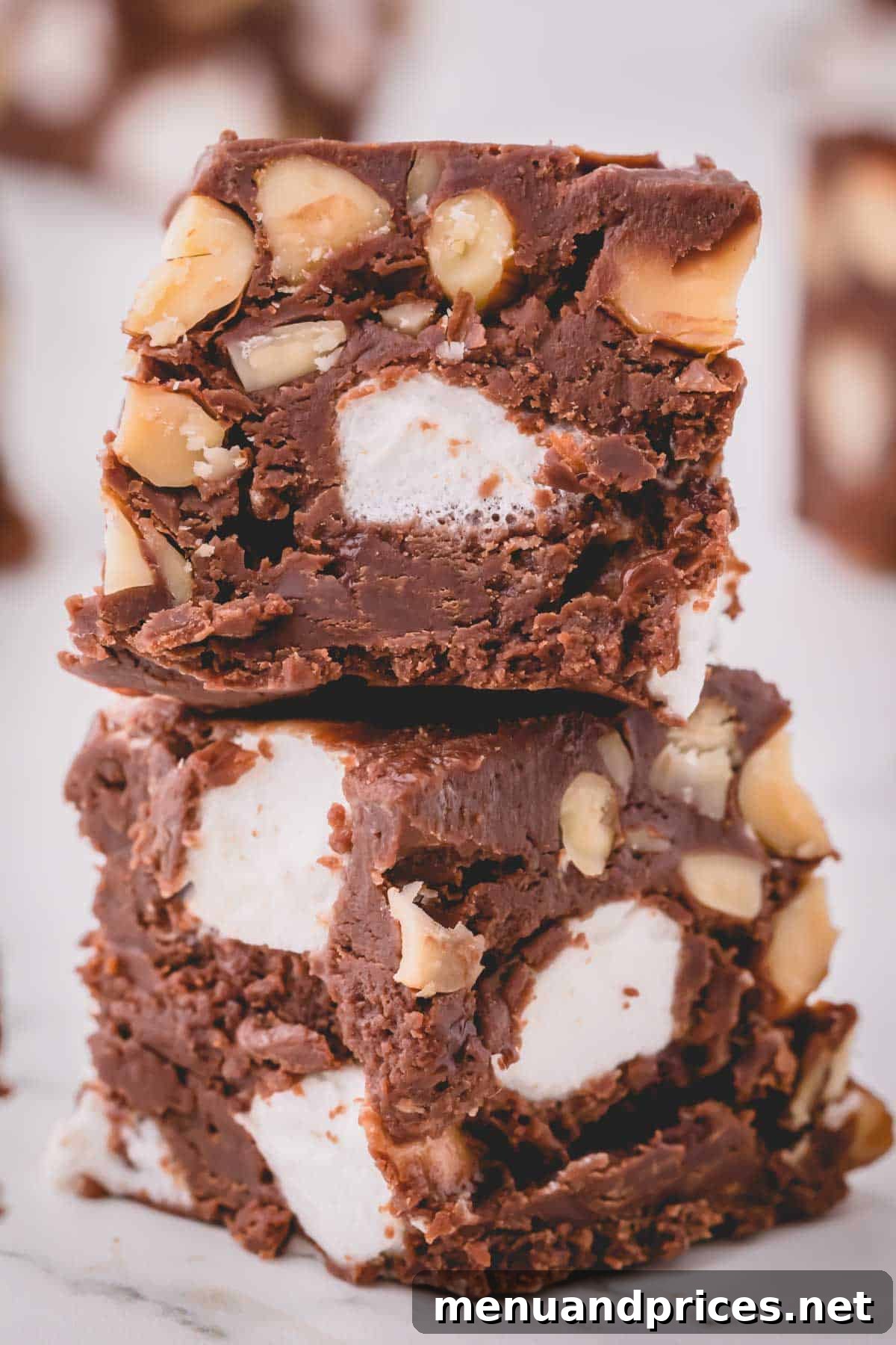 Creamy Rocky Road Indulgence 7 A neatly stacked pile of cut rocky road fudge pieces, showing the textures of chocolate, marshmallows, and almonds.