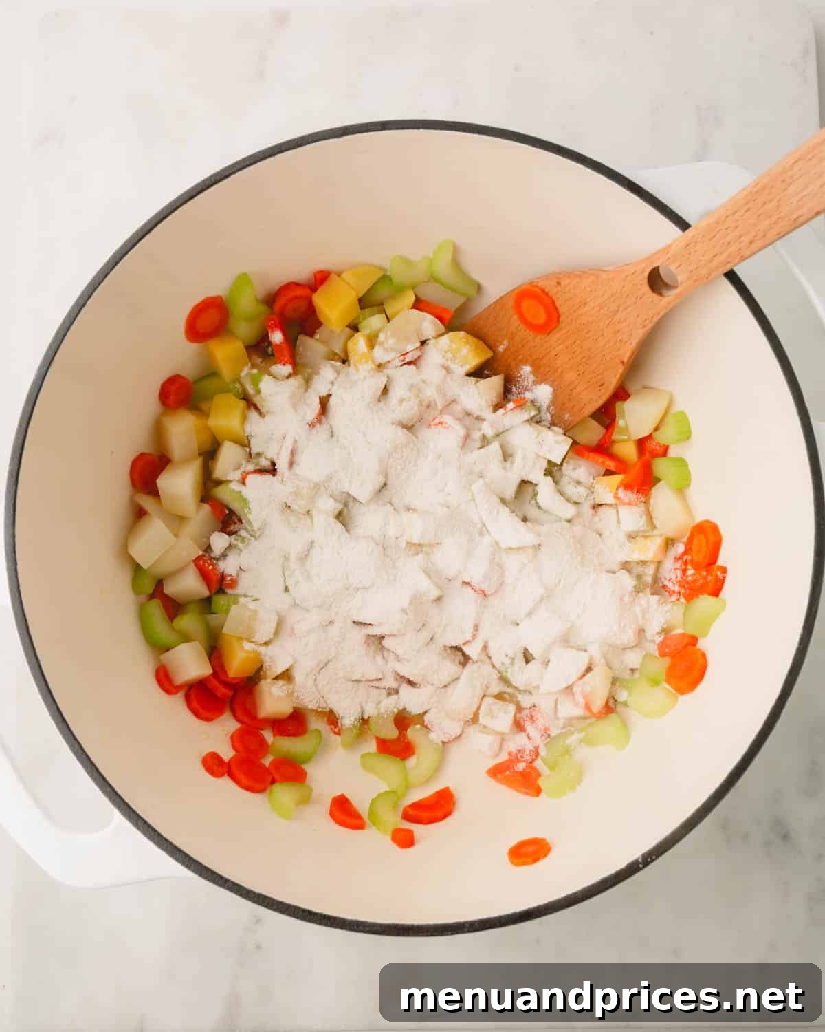 Pillowy Knoephla Noodle Soup 13 Chopped vegetables (carrots, celery, potatoes) in a Dutch oven are topped with a generous amount of flour, ready to be stirred.