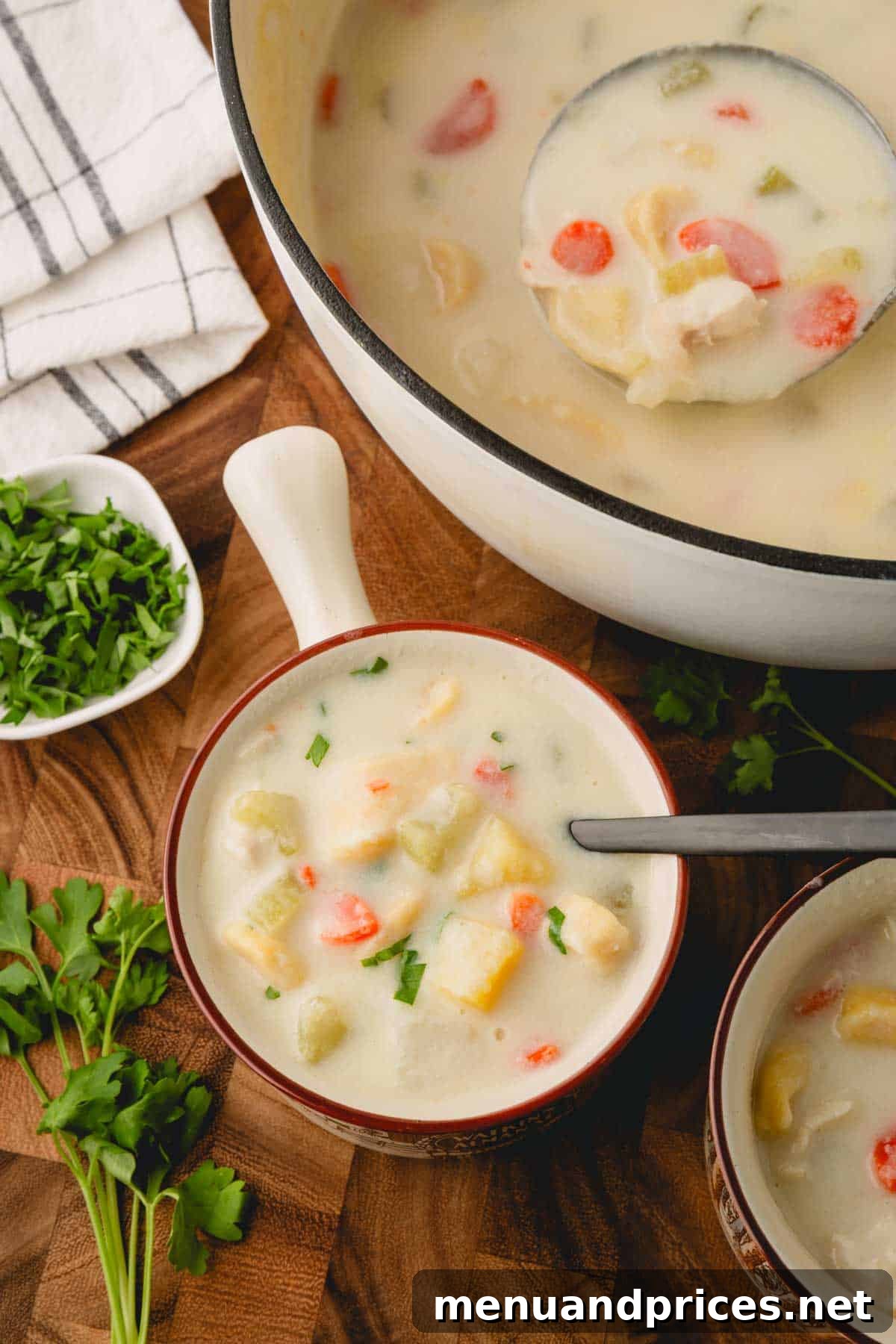 Pillowy Knoephla Noodle Soup 20 A comforting bowl of Knoephla soup sits invitingly next to a large pot, ready for serving.