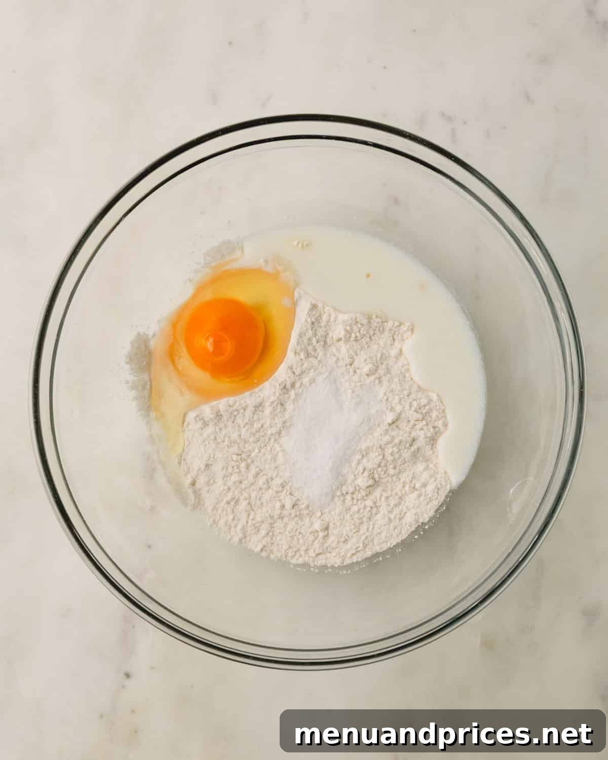 Pillowy Knoephla Noodle Soup 8 Knoephla ingredients, including flour, egg, and milk, are initially combined in a clear glass mixing bowl.