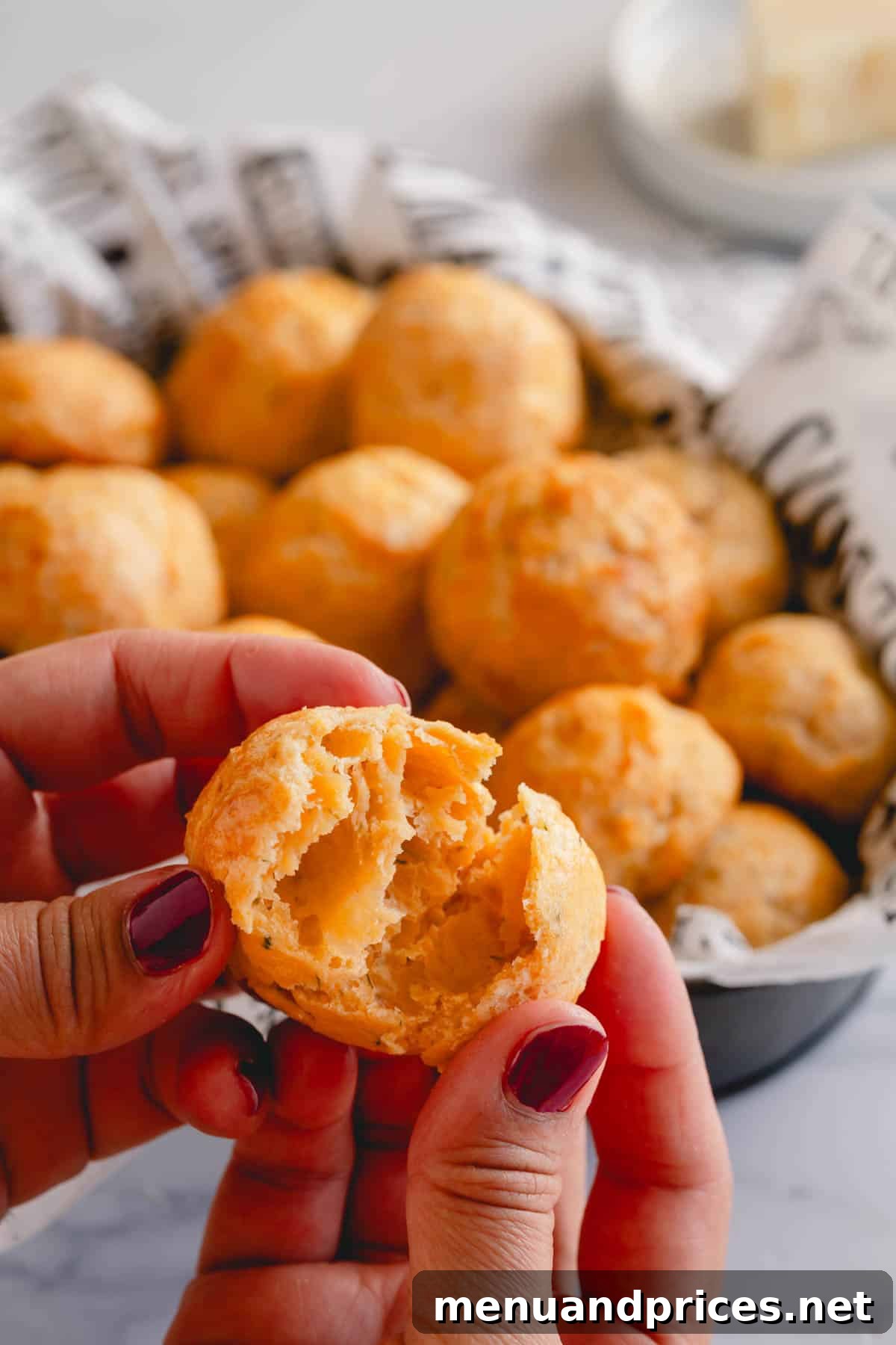 Fluffy Havarti Cheese Gougères 12 A close-up of a golden cheese puff torn in the middle, revealing its characteristic hollow, airy center and crispy texture.