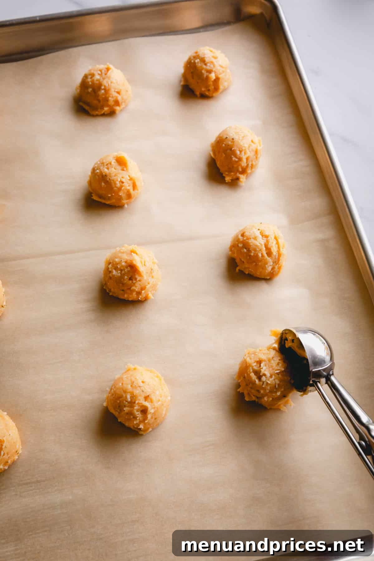 Fluffy Havarti Cheese Gougères 9 Using a cookie dough scoop to portion cheese puff dough onto a parchment-lined baking sheet, ensuring even spacing.