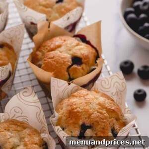 A batch of freshly baked blueberry cheesecake muffins on a wire rack, showcasing their golden-brown tops and visible blueberries.