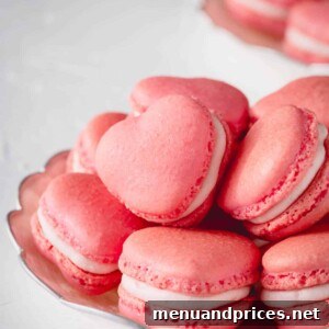Pink heart-shaped macarons stacked on a plate.