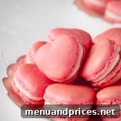Pink heart-shaped macarons stacked on a plate.