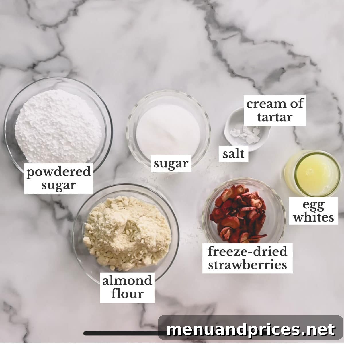All the ingredients for making strawberry macarons, neatly arranged on a white surface.