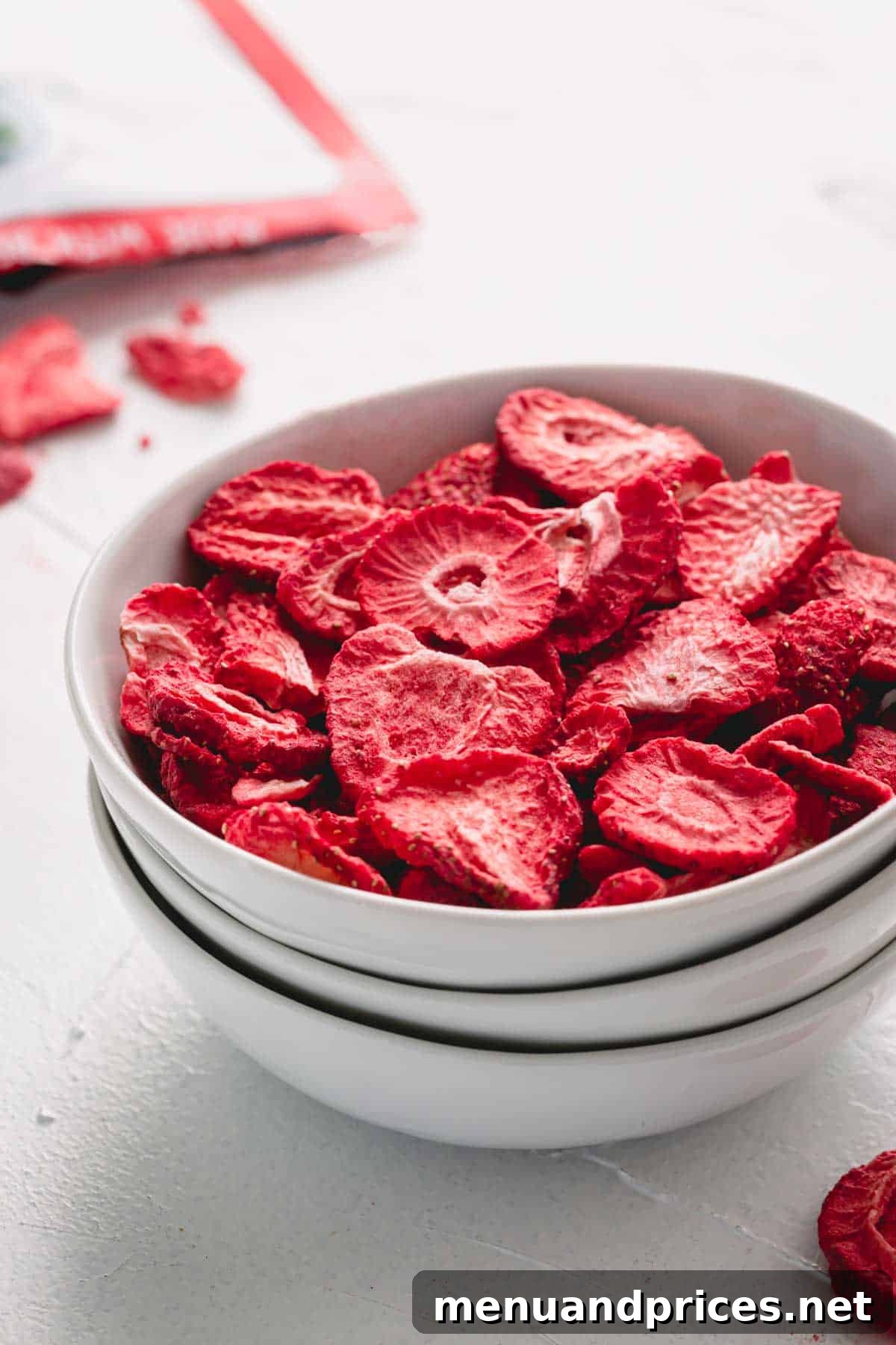 A white bowl filled with light, crispy freeze-dried strawberries.