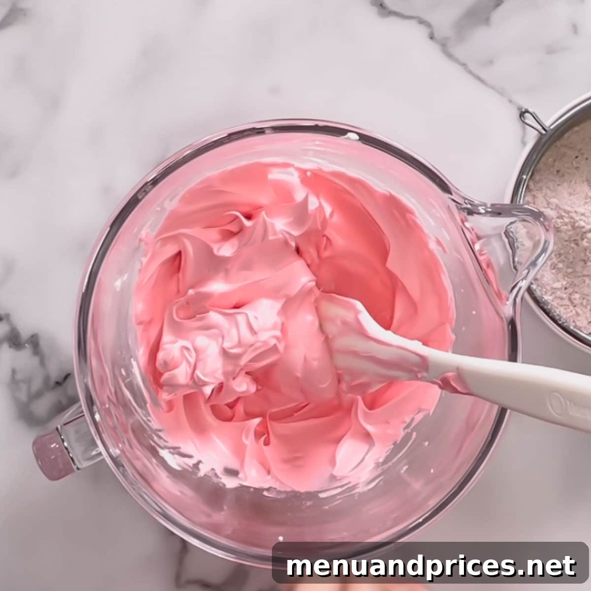 A glistening glass bowl of perfectly whipped pink meringue, showcasing its stiff peaks.