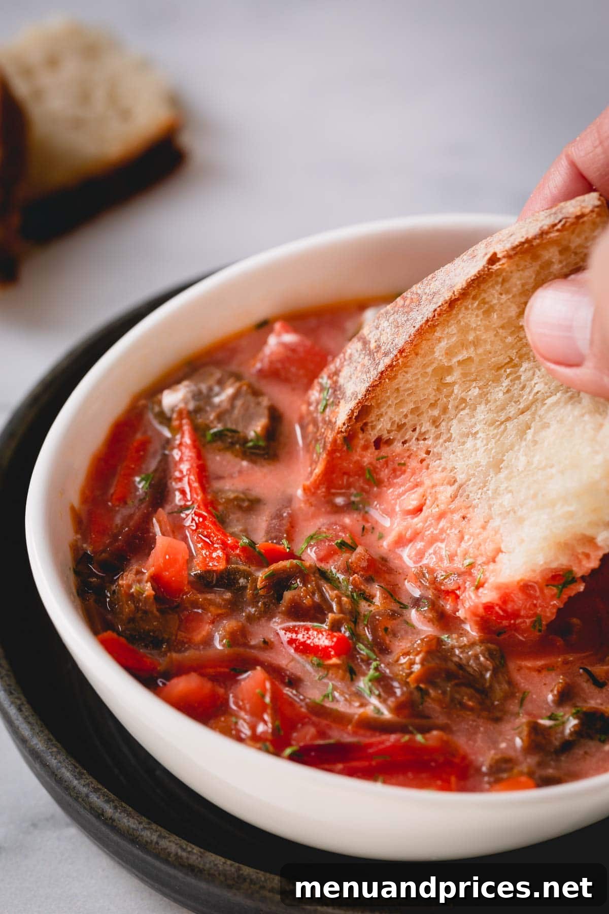 Hearty Beef Borscht 3 Bowl of soup with a slice of bread dipped in it.
